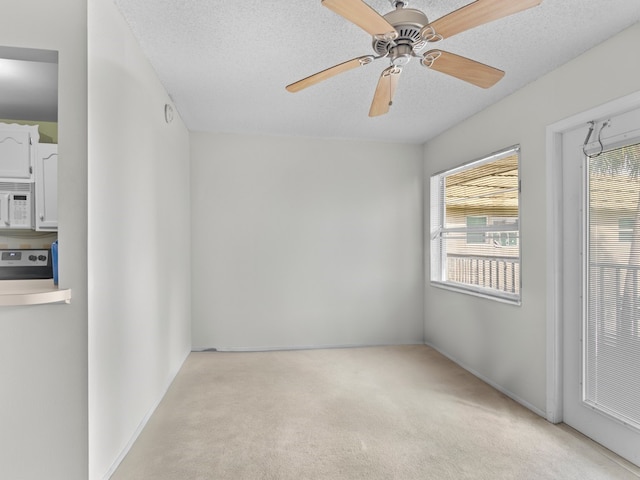 spare room featuring a textured ceiling, light carpet, and ceiling fan