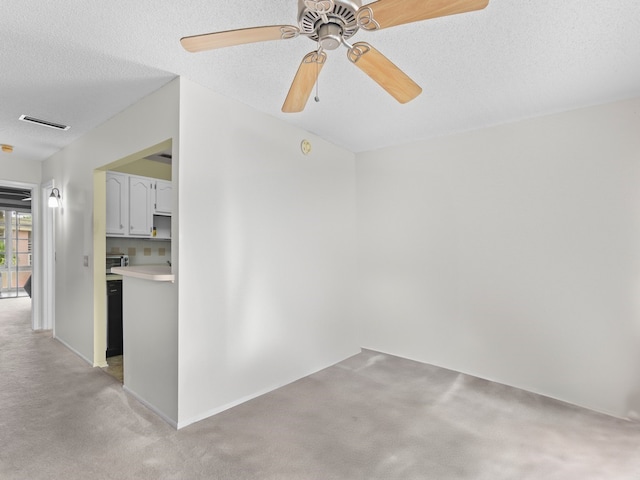 carpeted spare room with a textured ceiling and ceiling fan