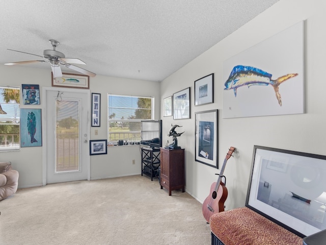 living area with light colored carpet, a textured ceiling, and ceiling fan