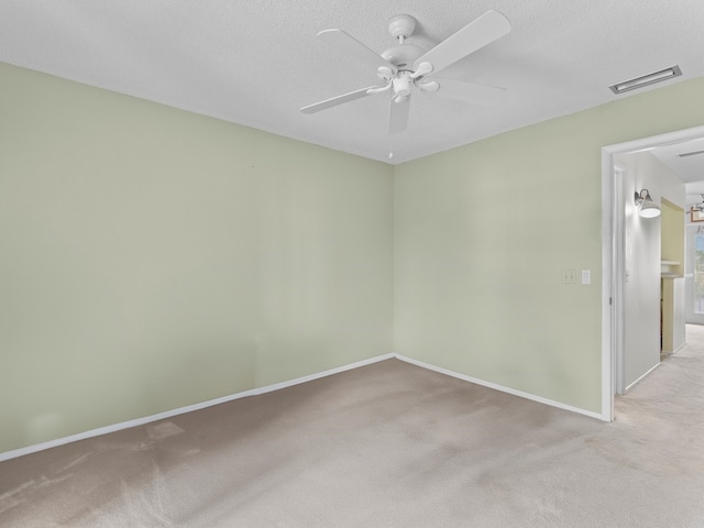 carpeted spare room featuring ceiling fan and a textured ceiling