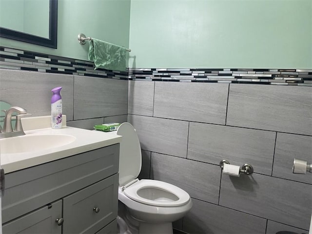 bathroom with vanity, tile walls, and toilet