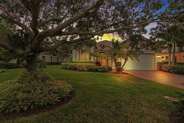 1274 River Reach Dr, Vero Beach, FL 32967 - view of property hidden behind natural elements featuring an attached garage, stucco siding, a lawn, and driveway