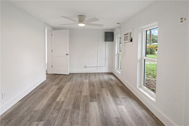 unfurnished bedroom featuring light hardwood / wood-style floors, multiple windows, ceiling fan, and a wall mounted air conditioner