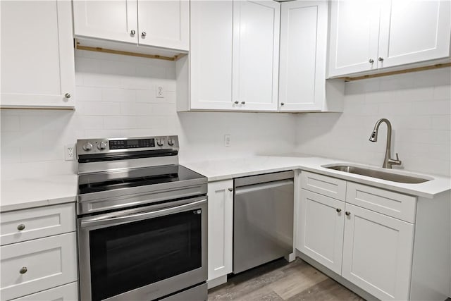 kitchen featuring appliances with stainless steel finishes, white cabinetry, a sink, and decorative backsplash