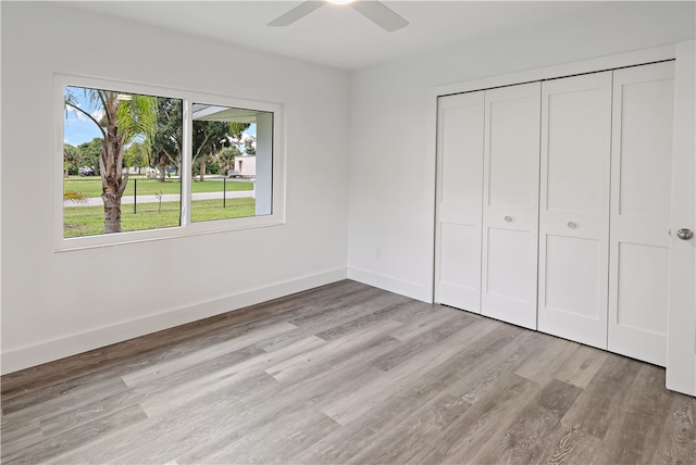 unfurnished bedroom with light wood-type flooring, ceiling fan, and a closet