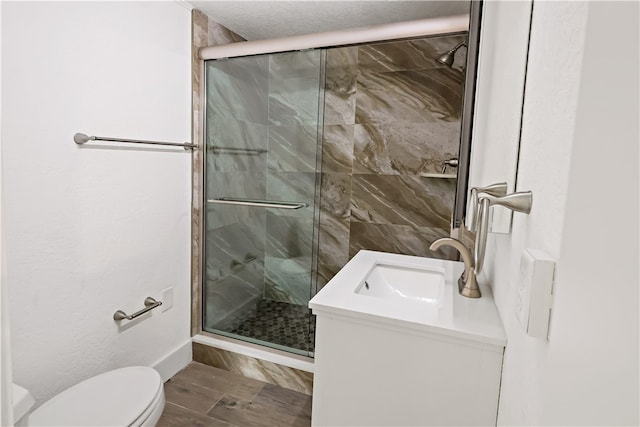 bathroom featuring vanity, a textured ceiling, hardwood / wood-style flooring, toilet, and a shower with shower door