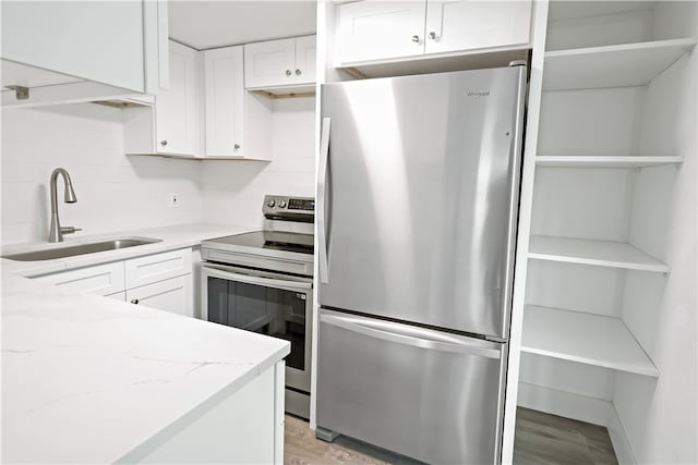 kitchen featuring stainless steel appliances, sink, tasteful backsplash, light stone countertops, and white cabinetry