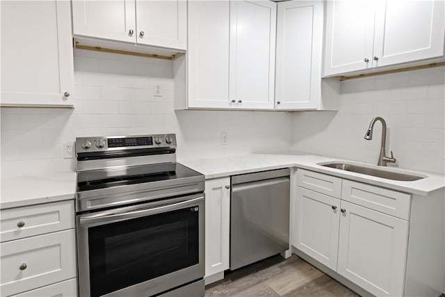 kitchen featuring white cabinetry, sink, light stone counters, and stainless steel appliances