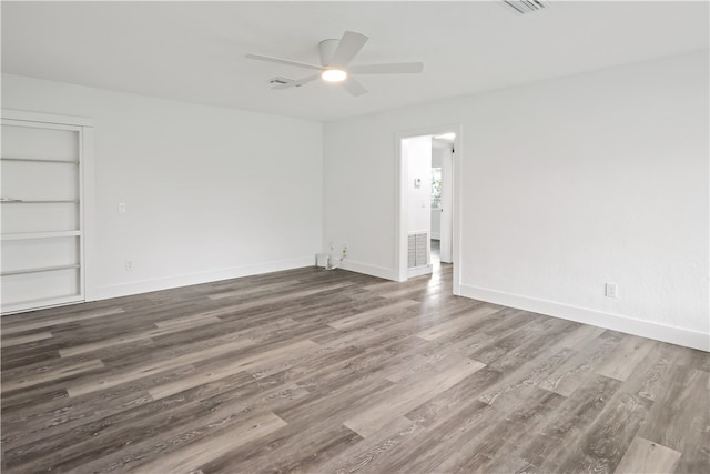 empty room with ceiling fan, wood-type flooring, and built in features