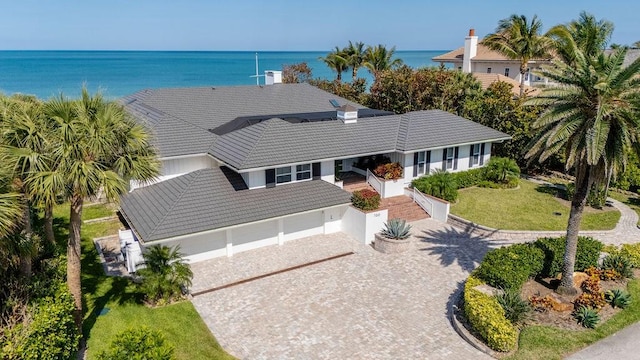 view of front of house with a tiled roof, a water view, decorative driveway, a porch, and a garage