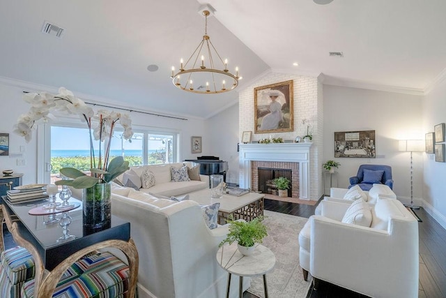 living room with dark wood finished floors, a notable chandelier, a brick fireplace, and visible vents