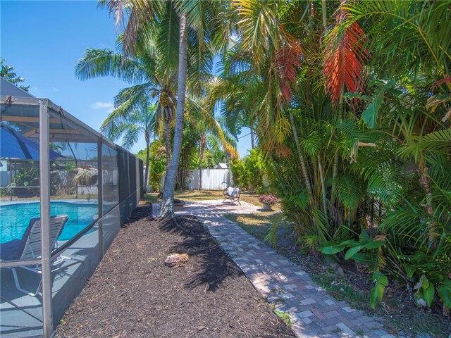 view of yard featuring glass enclosure, fence, and a fenced in pool