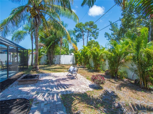 view of yard with a lanai, a patio, a fire pit, and a fenced backyard