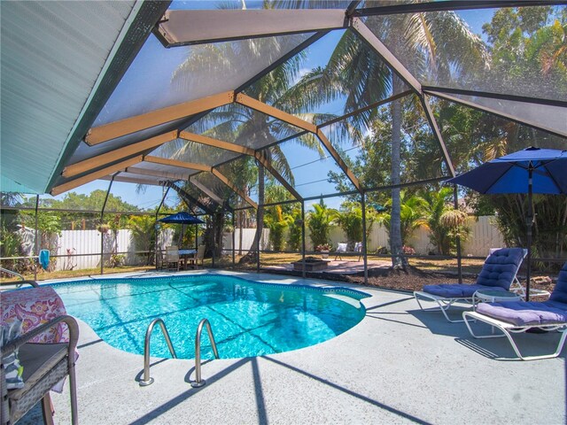 view of swimming pool with a patio, a fenced backyard, glass enclosure, and a fenced in pool