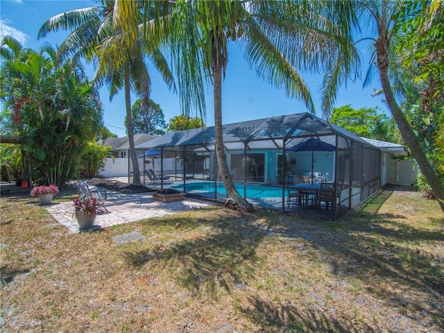 outdoor pool featuring a yard, fence, a patio area, and glass enclosure