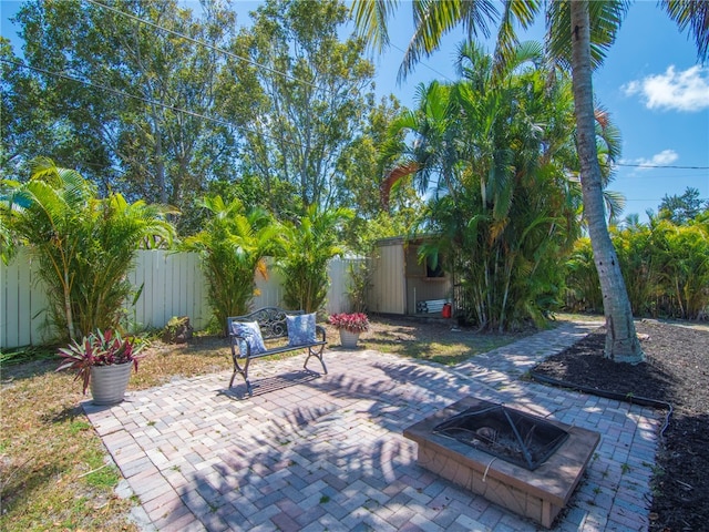view of patio / terrace with a fenced backyard, an outbuilding, an outdoor fire pit, and a shed