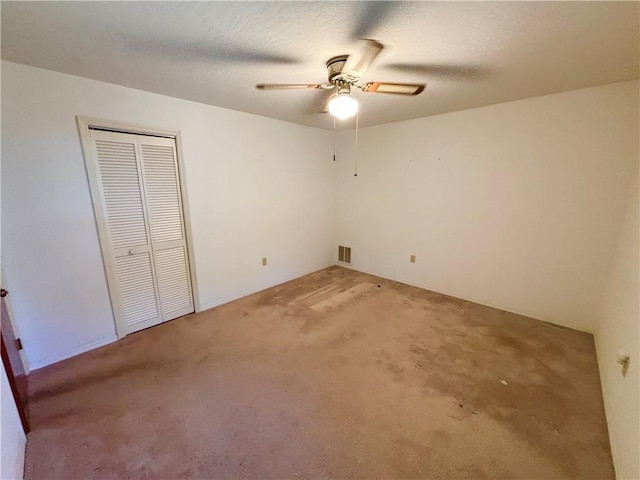 unfurnished bedroom with a textured ceiling, a ceiling fan, visible vents, a closet, and light carpet