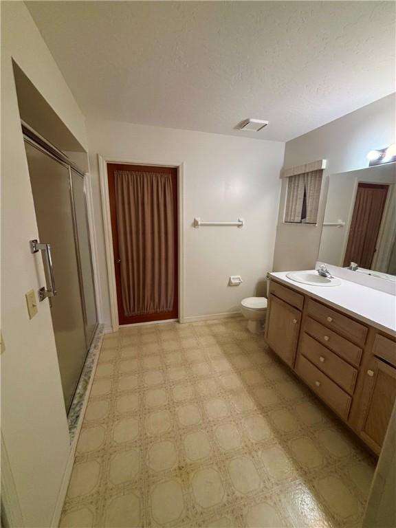 full bath featuring tile patterned floors, toilet, a stall shower, a textured ceiling, and vanity