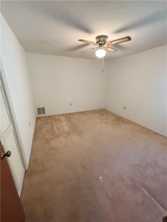 carpeted empty room featuring a textured ceiling, visible vents, and ceiling fan
