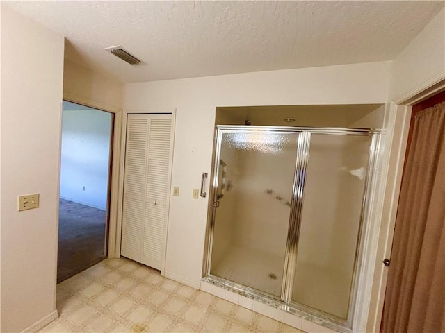 bathroom featuring tile patterned floors, visible vents, a textured ceiling, and a shower stall