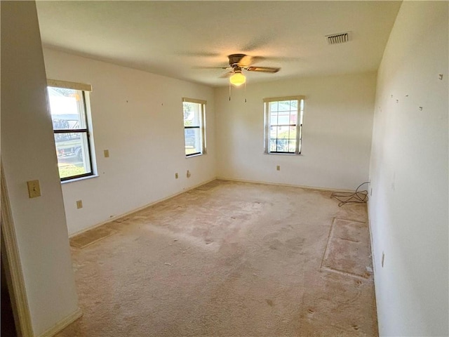 carpeted spare room featuring visible vents and ceiling fan
