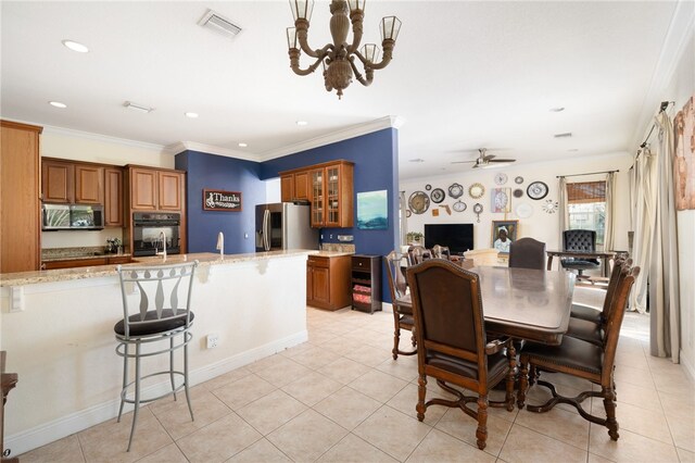 tiled dining area featuring ornamental molding and ceiling fan with notable chandelier