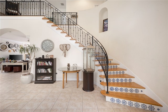 staircase with a towering ceiling and tile patterned floors