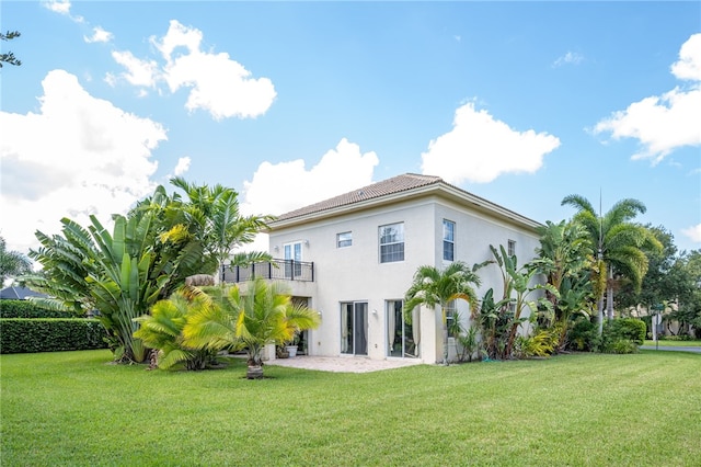 back of house featuring a lawn and a balcony