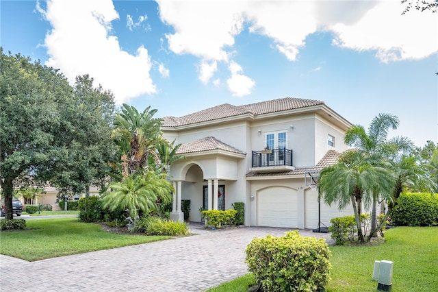 mediterranean / spanish house with a garage and a front lawn