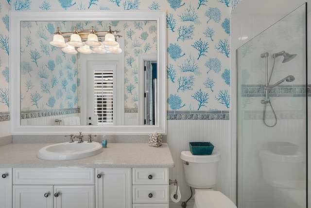 bathroom with a shower with door, vanity, and toilet