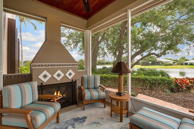 sunroom with a water view, wood ceiling, and an outdoor fireplace