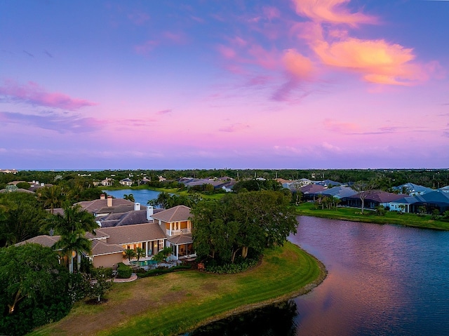 aerial view at dusk featuring a water view