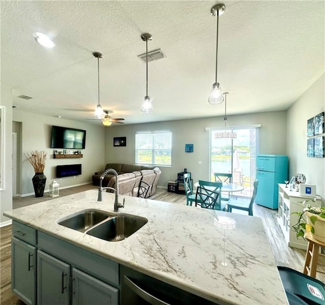 kitchen with light stone countertops, ceiling fan, sink, white refrigerator, and decorative light fixtures