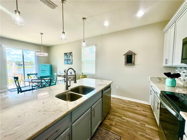 kitchen with white cabinetry, light stone countertops, sink, pendant lighting, and appliances with stainless steel finishes