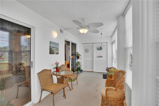 sitting room featuring light carpet, a textured ceiling, and ceiling fan