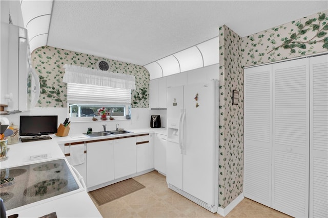 kitchen featuring white fridge with ice dispenser, sink, stovetop, a textured ceiling, and white cabinets