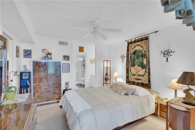 carpeted bedroom with ensuite bath, ceiling fan, and a textured ceiling