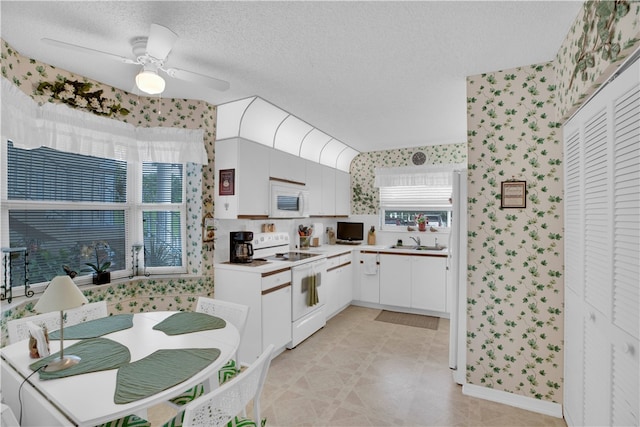 kitchen with ceiling fan, sink, a textured ceiling, white appliances, and white cabinets