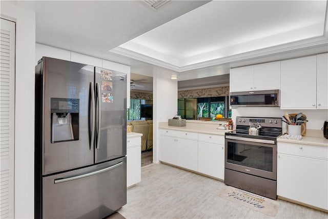 kitchen featuring light hardwood / wood-style flooring, stainless steel appliances, a raised ceiling, and white cabinets