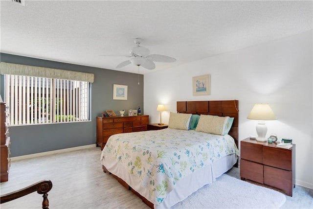 bedroom with ceiling fan, light hardwood / wood-style floors, and a textured ceiling