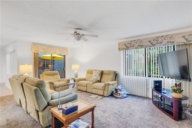 living room featuring ceiling fan, carpet flooring, and a textured ceiling