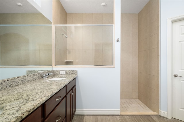 bathroom featuring a tile shower, vanity, hardwood / wood-style flooring, and a textured ceiling