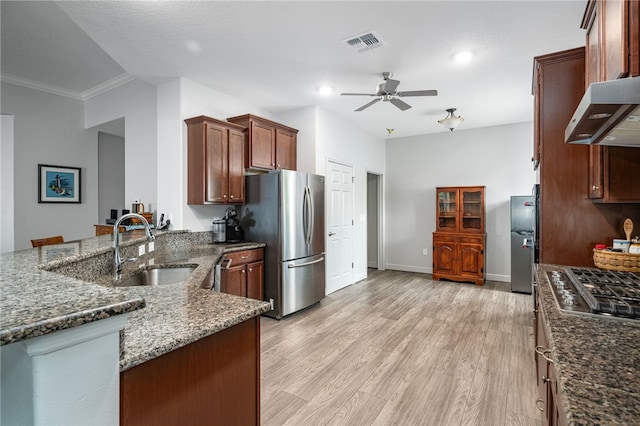 kitchen with sink, light hardwood / wood-style flooring, kitchen peninsula, dark stone counters, and appliances with stainless steel finishes