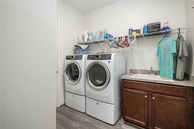 washroom with cabinets, separate washer and dryer, light hardwood / wood-style flooring, and sink