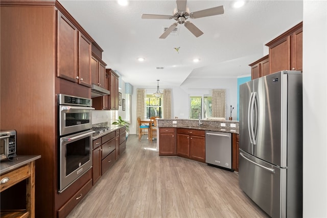 kitchen featuring ceiling fan, hanging light fixtures, stainless steel appliances, light stone counters, and light hardwood / wood-style flooring