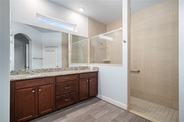 bathroom featuring a tile shower, vanity, and a textured ceiling