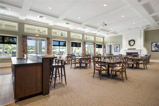 dining area with light carpet, coffered ceiling, sink, beam ceiling, and a fireplace