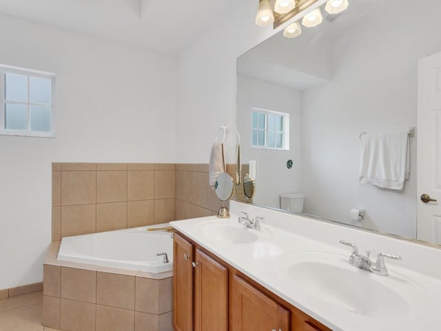 bathroom featuring a relaxing tiled tub, vanity, toilet, and tile patterned flooring