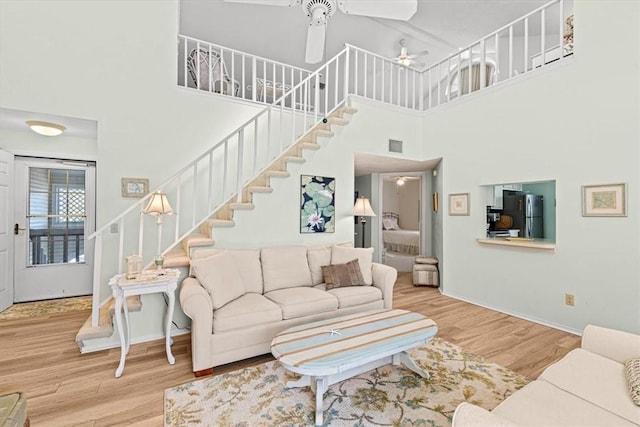 living room featuring wood-type flooring, a towering ceiling, and ceiling fan