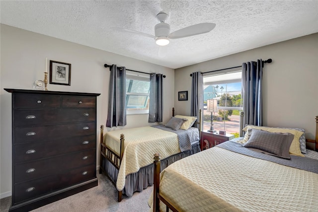 carpeted bedroom with multiple windows, a textured ceiling, and ceiling fan